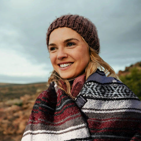 Woman outdoors wrapped in Authentic Handmade Falsa Baja Blanket Soft And Lightweight Mexican Throw for Yoga, Beach, Camping, Picnics, Car or Truck.