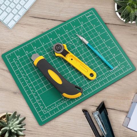 Cutting Mat 12 By 18 Inch Self Healing Double Sided For Sewing And Quilting Fabric Cutting Mat For Crafts Desktop Craft Mat Durable PVC Work Surface Great For Diyers And More with tools on a desk.