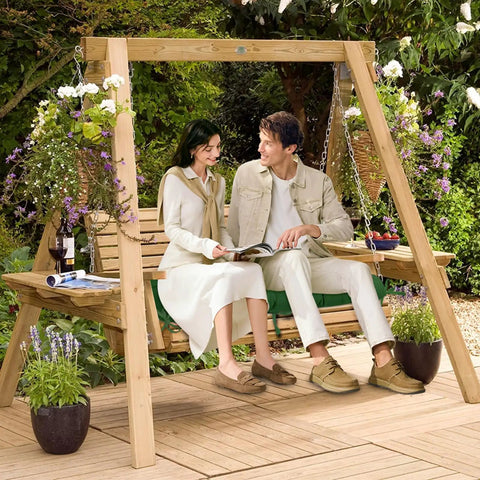 Couple sitting on a wooden garden swing surrounded by plants and flowers on a patio.