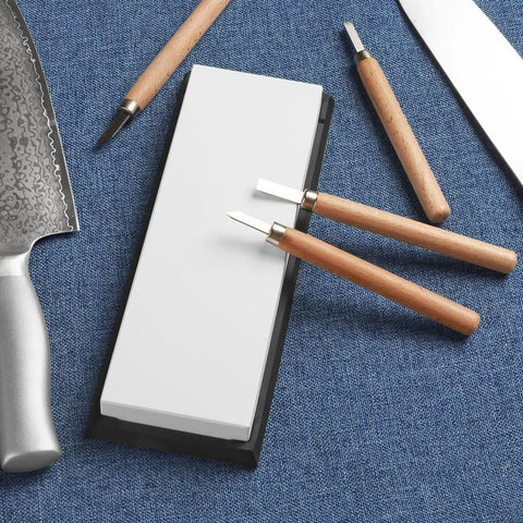 Professional Glass Sharpening Stone Whetstone 15,000 Grit For Razor Sharp Knives on blue surface with carving tools