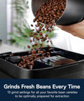 Certified Renewed Fully Automatic Espresso Machine With Built In Grinder And No Fuss Milk Frother Programmable One Touch Coffee Maker pouring fresh coffee beans into grinder.