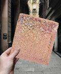Hand holding a rose gold bubble mailer, part of Rose Metallic Padded Mailers 20 Pack 6x5 Inch Self Sealing Cushioned Shipping Bags For Mailing Clothes And Small Packages Durable Protective Packaging That Just Works For Quick Ship, in an urban background