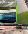 Tent interior with a bed covered in plaid blankets and two pillows, showcasing the Two Pack Camping Pillow For Sleeping On The Go.
