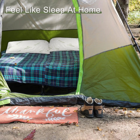 Tent interior with a bed covered in plaid blankets and two pillows, showcasing the Two Pack Camping Pillow For Sleeping On The Go.