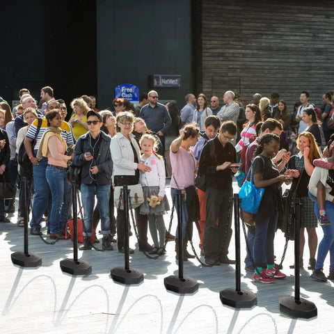 Crowd guided by Four 34 Inch Plastic Traffic Delineator Cones With Weighted Fillable Base Portable Safety Posts in a line.