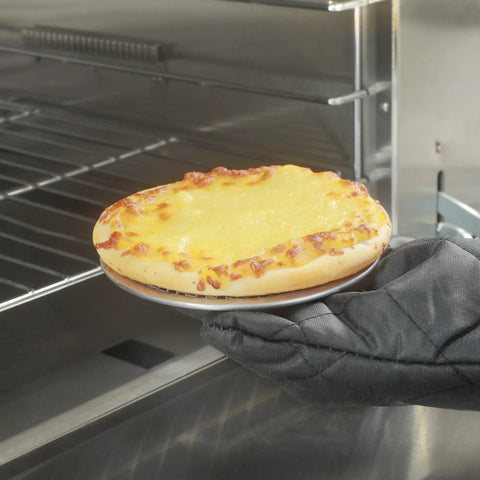 Gloved hand placing pizza on Aluminum 6 Inch Pizza Screen Pack Of 144 For Crispy Crust And Fast Even Baking Lightweight And Stackable in oven