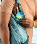 Person holding 20 Pack Mosquito Repellent Bracelets For Adults And Kids Natural DEET Free Bands next to a backpack