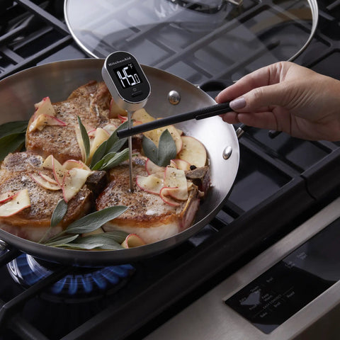 Digital Instant Read Kitchen Thermometer With Pivoting Backlit Display For Easy Reading From Any Angle Ultra Fast Under Six Seconds Wide Minus Forty To Four Hundred Eighty Two Fahrenheit Range For Grill Masters Baking Candy Making And More Black in use checking temperature of meat in frying pan on stove.