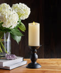 Realistic Moving Flame Pillar Candle With Flameless LED Lights, Unscented Ivory on black holder beside hydrangea bouquet