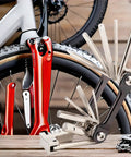 All In One Bike Multitool Kit With Chain Breaker And Tire Repair, lightweight stainless steel, shown with bicycle wheel