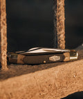 Solid As A Rock Pocket Folder With 2 Inch Clip Point Blade Crafted From High Carbon Stainless Steel and Rough Cut Sawcut Grip on rustic wood.