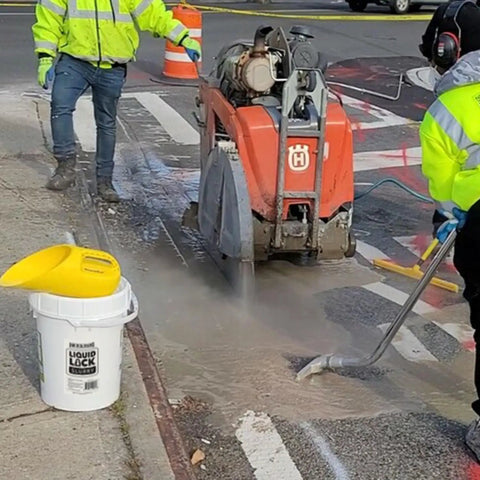 Liquid Lock Slurry Absorbent Powder in a 5 gallon pail with scoop on construction site with machinery
