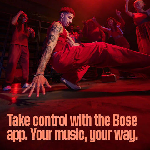 Group of dancers performing energetically in a dimly lit room with text overlay promoting the Bose app for music control.