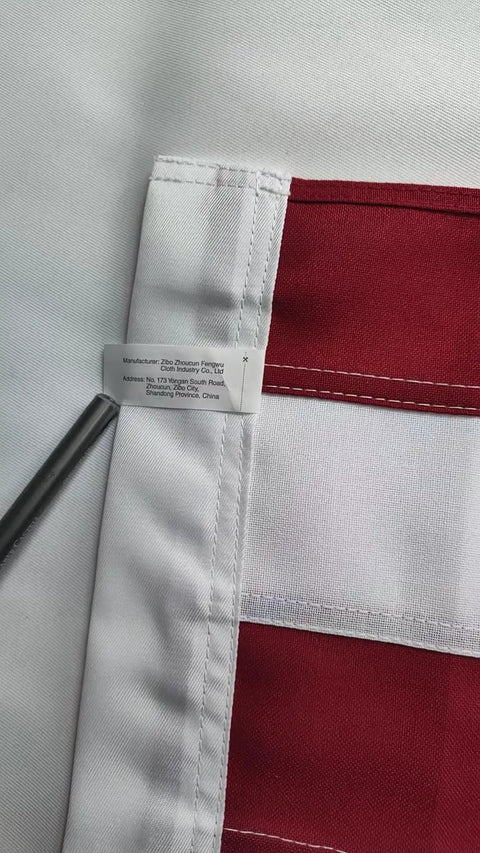 Close-up of edge stitching on Outdoor 3x5 Foot American Flag Built Tough Deluxe Heavy Duty Spun Polyester with sewn stripes tag visible.