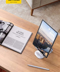 Adjustable Tablet Stand For 4 To 13 Inch Tablets And Phones Desktop Holder For iPad Pro Models Air Mini Kindle Switch Galaxy Tab And More Ideal Office Desk Accessory For Home And Work holding tablet on wooden desk with magazine and pen
