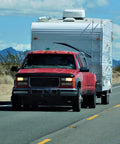 Red truck towing a white camper trailer on a desert road, demonstrating the Slick Trailer Wiring Junction Box For Rv And Camper Lights Seven Gang Automotive Connector Rewiring Kit With Bold Markings For Quick Plugging And Hassle Free Hookup Installation.