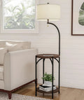 Go-To Space Saving Floor Lamp With End Table And USB Port next to a sofa in a living room, displaying black metal frame and wooden shelves.