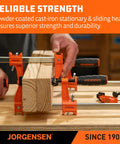 Jorgensen 2-pack 24-inch medium-duty steel bar clamps, orange, securing a wooden block on a workbench.
