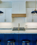 Industrial Caged Dome Metal Ceiling Light in Brushed Brass and Navy Blue Two Tone Finish hangs over a modern kitchen island