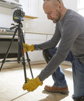 Person adjusting BT 150 Compact Tripod With Extendable Height For Line Lasers Point Lasers Jobsite Ready in a kitchen setup