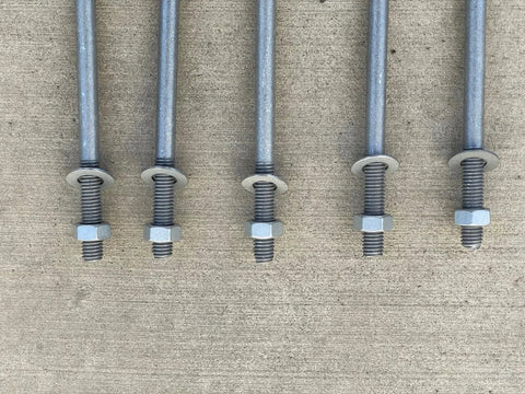 Five half inch by ten inch threaded concrete anchor L bolts with nuts and washers on concrete
