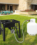 Outdoor propane regulator with 48-inch stainless braided hose connected to a black metal grill burner frame beside a white propane tank