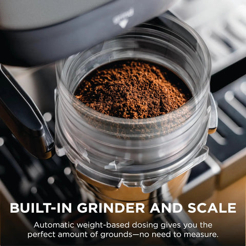 Brew Like A Pro At Home With This Triple Threat Espresso And Drip Coffee Maker Featuring Rapid Cold Brew Options Alongside Reliable Dual Shot Settings In Sleek Gunmetal Finish showing built-in grinder with coffee grounds.