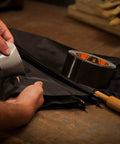 Hands using Heavy Duty Double Thick Black Duct Tape 1.88 Inch By 12 Yard Roll on black fabric, showing repair use.