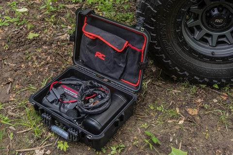 Tough As Nails Portable 12V Dual Cylinder Air Compressor Pump 150 Psi And 6 16 Cfm Fast Tire Inflator inside a sturdy case on dirt.