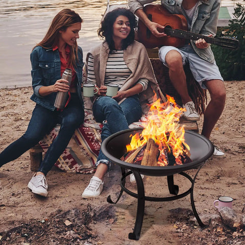 22 Inch Outdoor Fire Pit With Mesh Lid And Log Grate For Backyard Deck Camping And Picnics Durable Steel Construction Heat Resistant And Easy To Carry Portable Fire Pit For Warm Evenings by a lakeside with friends gathered around.
