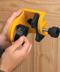 Hands adjusting yellow and black door lock installation kit with C-clamp design, for metal or wood doors, showing tool-free clamping.
