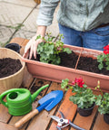Gardener using 30 Piece Mini Garden Shovel Set Colorful Metal Tools With Wooden Handles for planting flowers in a planter