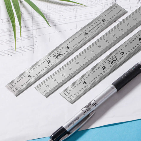 Three 6-inch stainless steel rulers on drafting paper, featuring metric and imperial markings from the Pro Grade Machinist Ruler Set