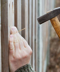 Person hammering Gold Finish Nail Kit With 600 Nails In Four Sizes For Picture Hanging And Woodworking into wooden fence