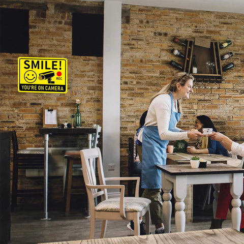 Smile You're On Camera Signs Two Pack Outdoor Video Surveillance Warning Signs 10x7 Rust Free Aluminum in a cafe setting