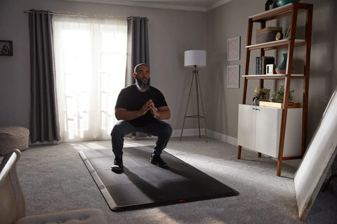 4x8 Gym Flooring Mat For Peloton Bike Elliptical Treadmill And Home Gym Setup Non Slip Floor Pad For Hardwood Or Carpet Just Unroll And Transform Any Room Into A Home Gym Ideal For Spin HIIT Zumba Cardio Training with man exercising