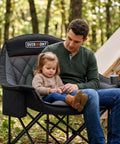 Man and child sitting on Oversized XL Camping Chair for Adults With 400 Pound Capacity Heavy Duty Padded Folding Seat Side Pocket Cup Holder Cooling Bag Included Ideal for Beach Camping RV Trips Outdoor Sports Garden and Lawn in forest