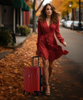 Red 20-inch hardshell carry-on luggage with 4 spinner wheels, front view beside a woman in a red dress on a city street.