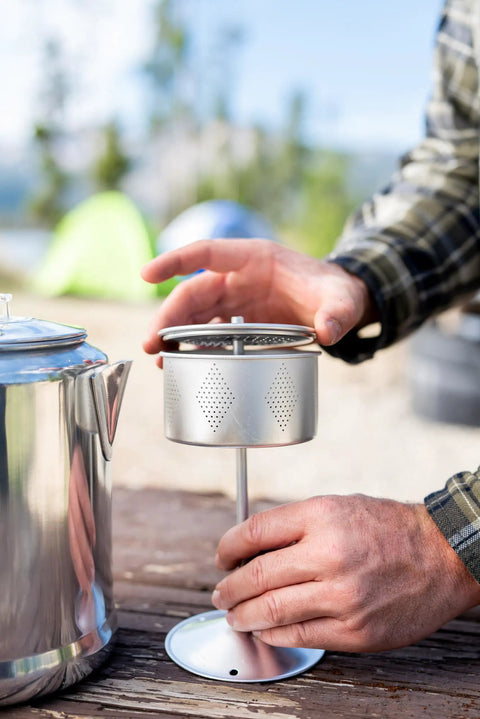 Hands assembling Camper's Percolator Coffee Pot For Camping 9 Cup Aluminum Brew Coffee Pot with stem and basket outdoors