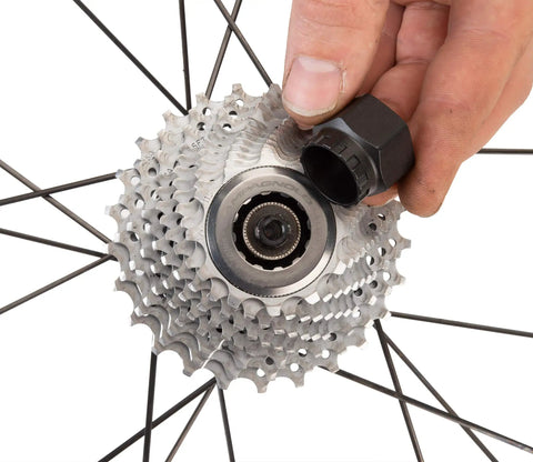 Hand holding Bottom Bracket And Lockring Tool For Campagnolo Cassettes BBT 5 And FR 11 near bicycle cassette