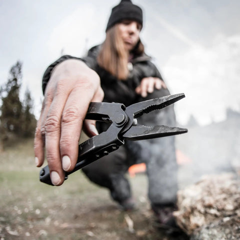 Person using 14-In-1 Multitool With Needlenose Pliers, Serrated Knife, Wire Crimper, Bottle Opener, Can Opener And Screwdriver outdoors