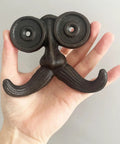 Badass Vintage Cast Iron Beard Shaped Wall Hook Kit held in hand, showcasing unique design for hanging coats and bags.