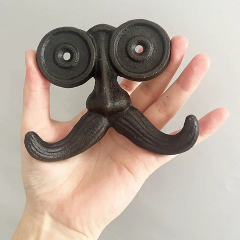 Badass Vintage Cast Iron Beard Shaped Wall Hook Kit held in hand, showcasing unique design for hanging coats and bags.