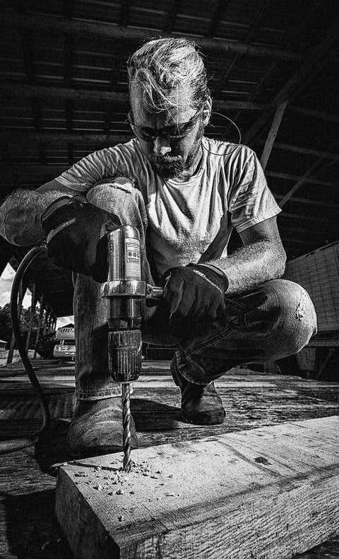 Man using a Half Inch Keyless Chuck Air Drill With Reversible Operation, 500 RPM, 0.5 HP, ergonomic grip on wooden surface.