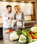 A couple enjoying cooking together in a modern kitchen with fresh vegetables on the counter.