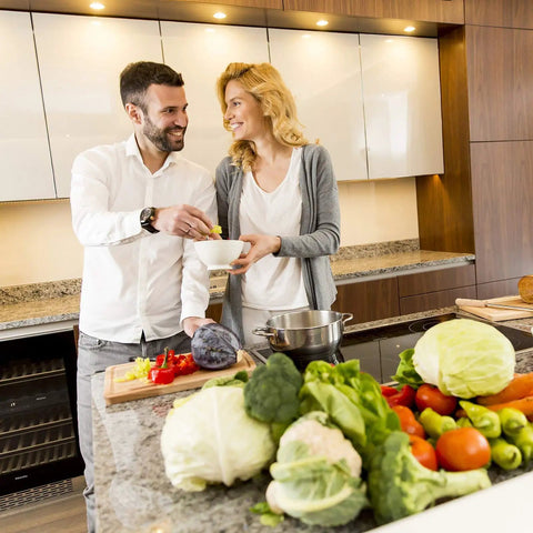 A couple enjoying cooking together in a modern kitchen with fresh vegetables on the counter.