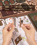 Hands assembling 3D Wooden Puzzle Bookstore With LED Lights Spellbound Miniature Kit, DIY home decor, instruction manual visible.