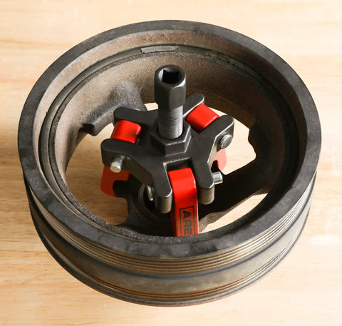 Harmonic Balancer Puller Kit For Cars And Trucks With Adjustable 3-Jaw Design in use, removing damper from engine pulley