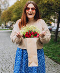 Woman holding 100 Pack Kraft Paper Gift Bags With Handles, Medium Brown 8x4.25x10.25 Inch Recycled Kraft Bags