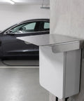 Heavy Duty EV Charger Protective Housing With Waterproof Outdoor Box Cover Built From Rock Solid Stainless Steel mounted beside a car.